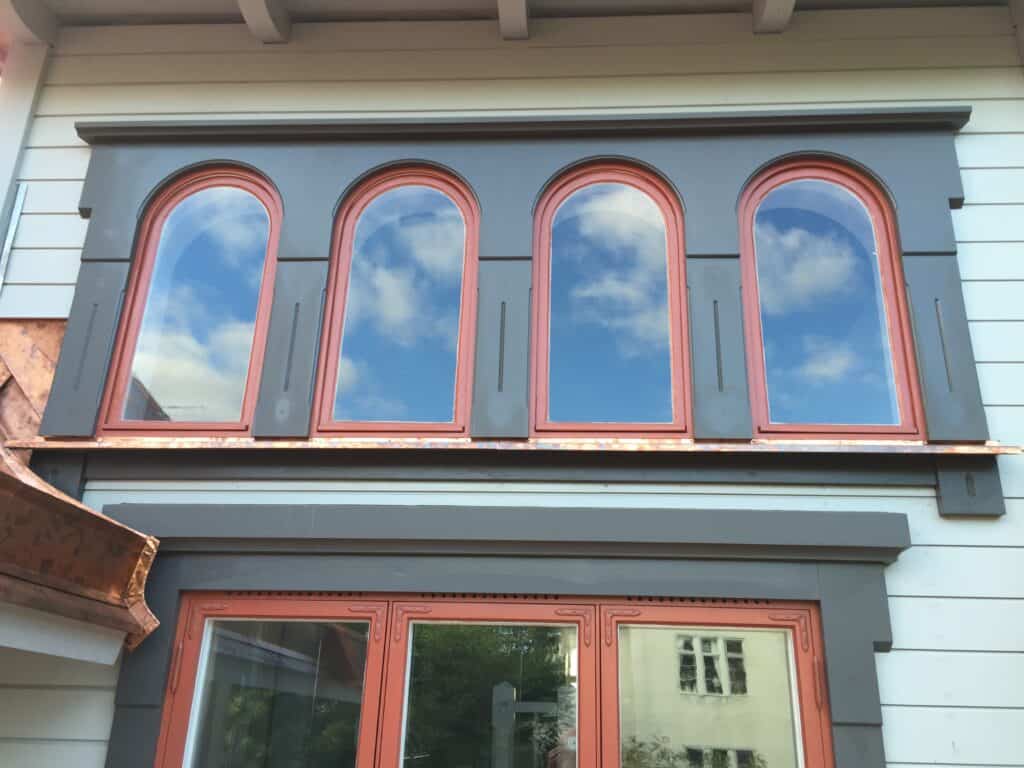Renoverade rundbågefönster med koppardetaljer på sekelskifteshus